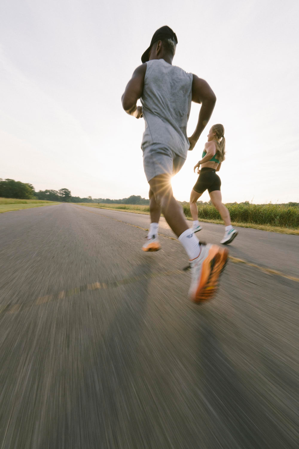 Two runners jogging on a road during sunset, showcasing athletic socks.