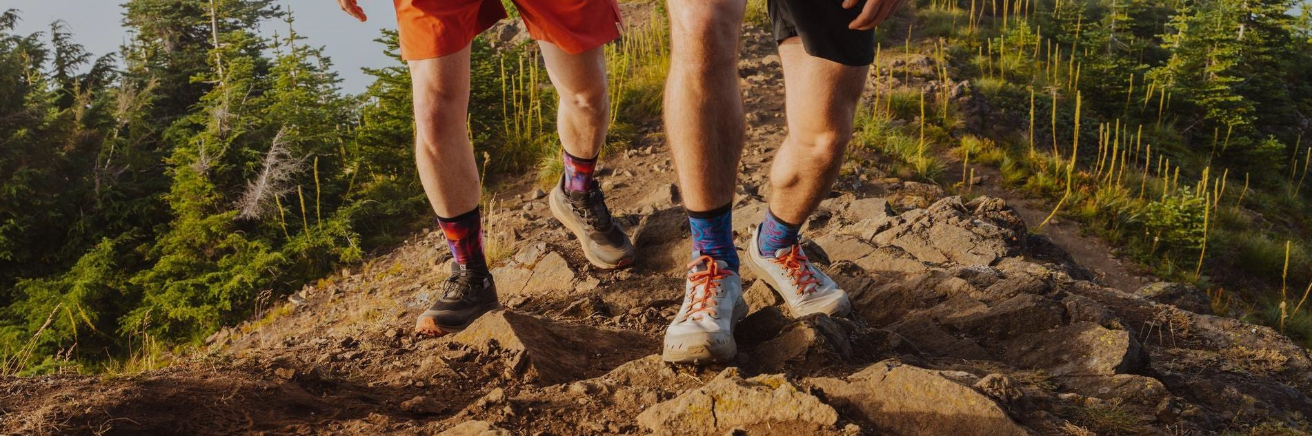 closeup of two hikers' legs wearing Swiftwick socks and trail running shoes on rugged dirt trail