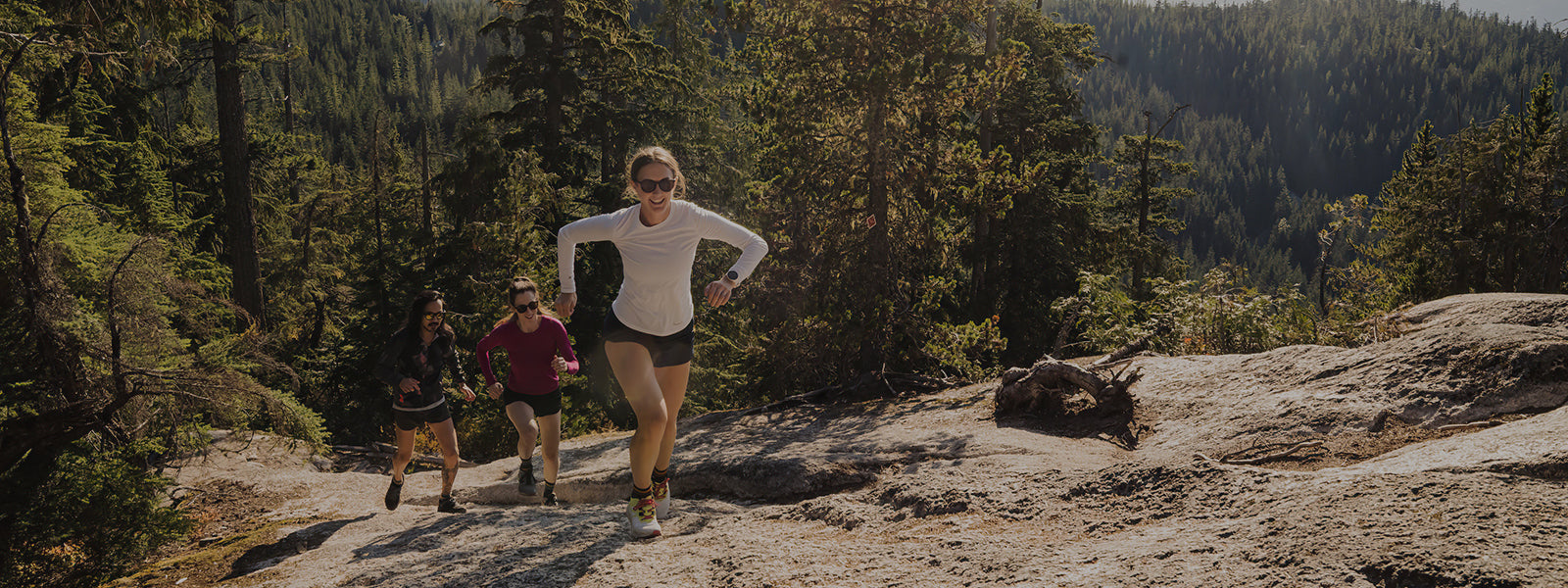 three people running on a trail wearing Swiftwick socks