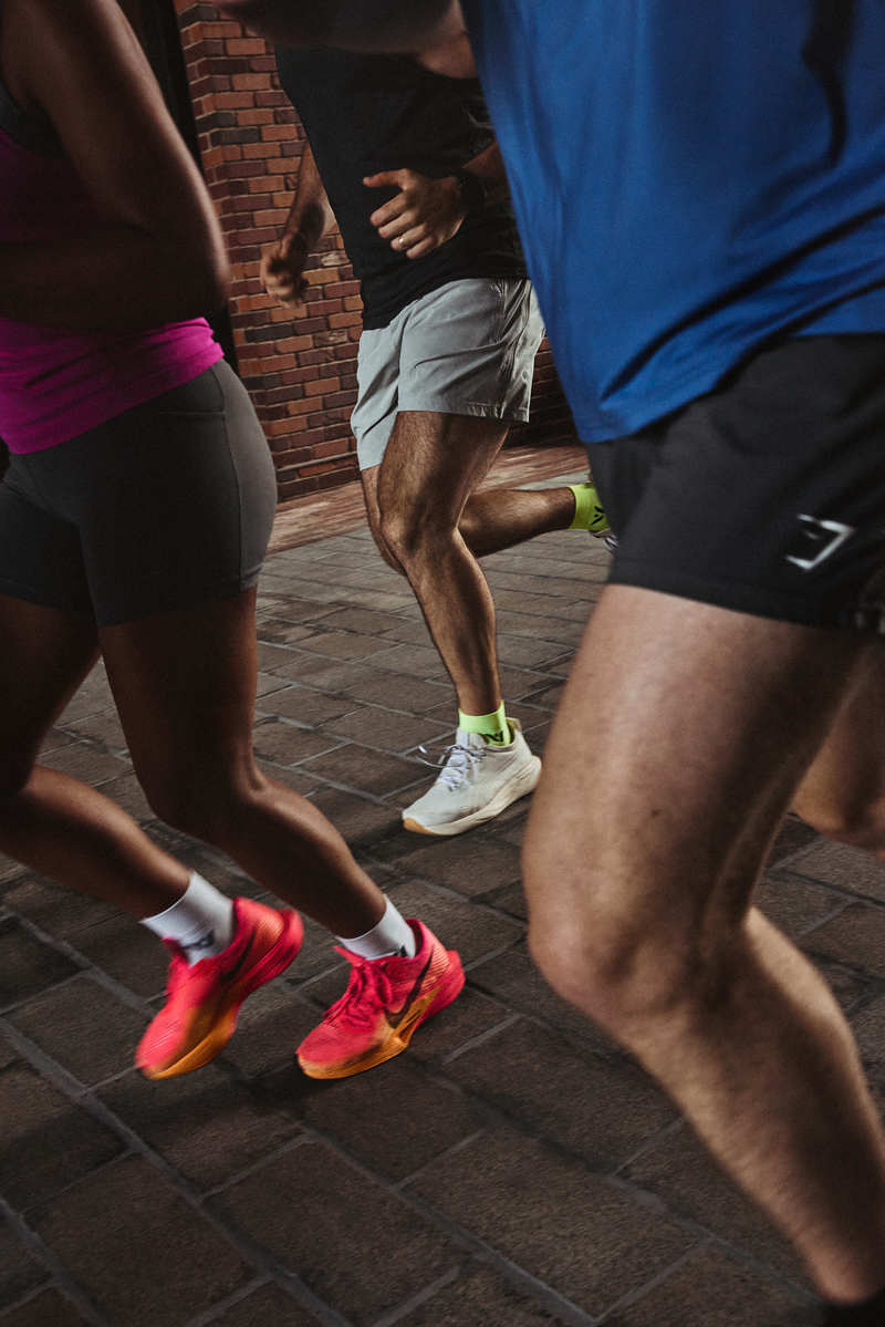 Three people running on brick sidewalk.