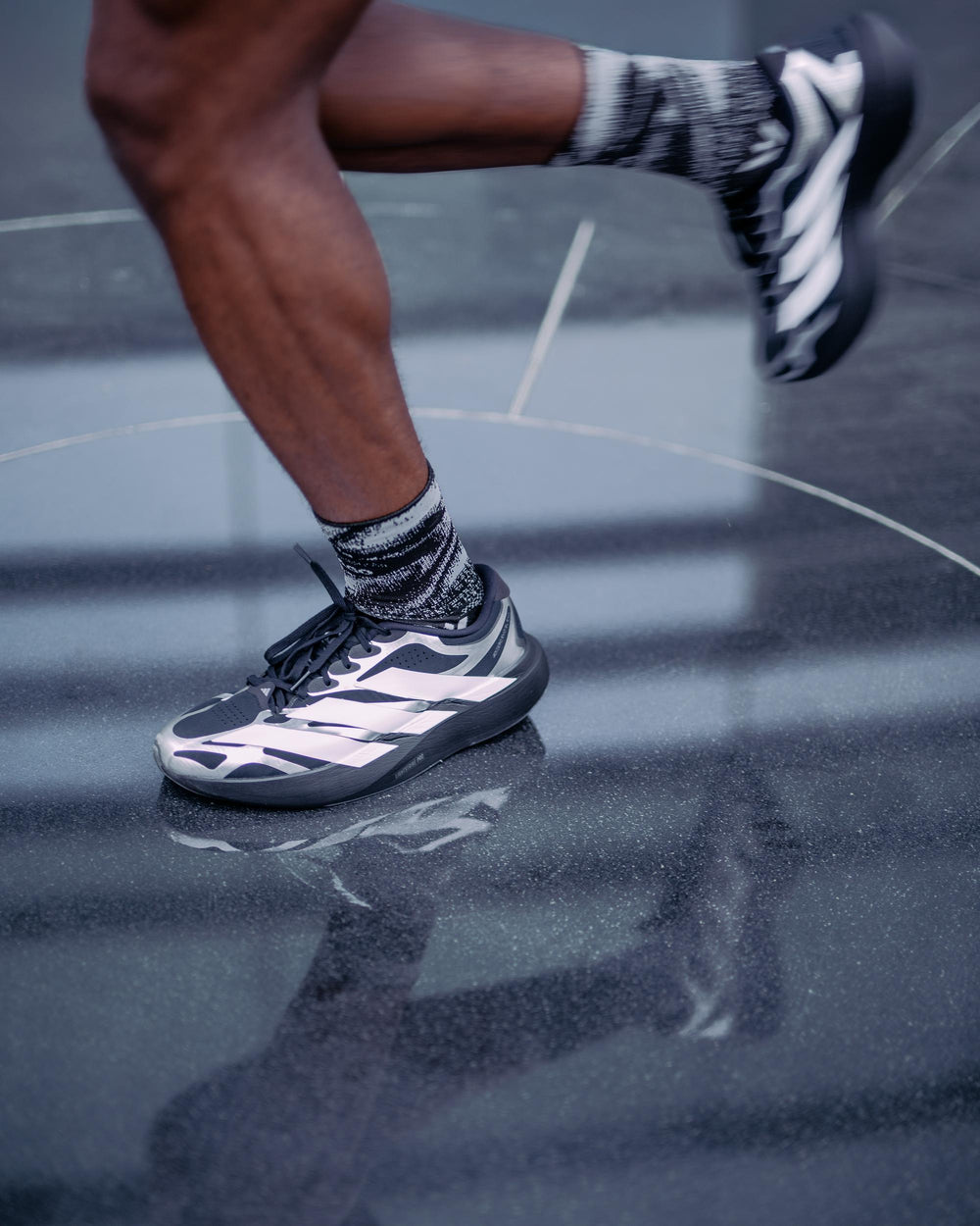 Runner mid-stride in Swiftwick Chicago socks and running shoes on a dark reflective surface