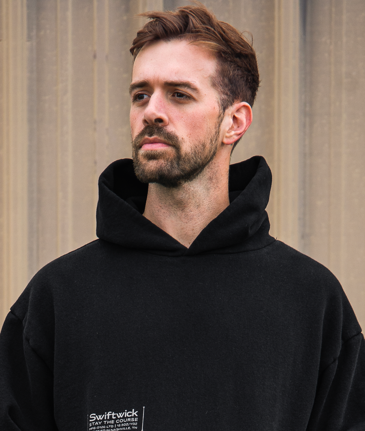 Man wearing a black hoodie with Swiftwick logo against a neutral background