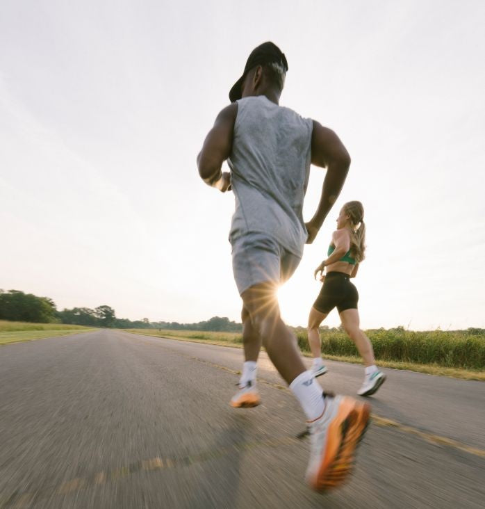 Two people running on a road with a sunlit background