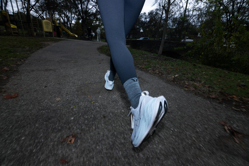 Closeup of runner's legs as they run along a sidewalk.