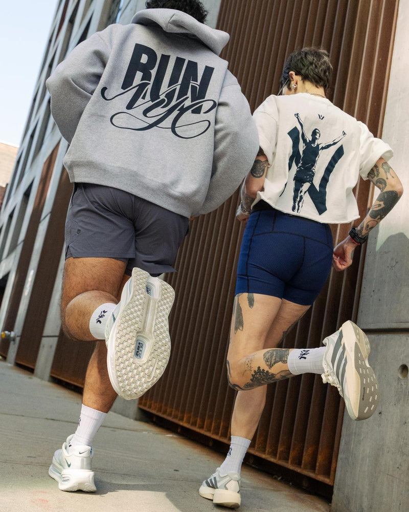 Back view of two people running together in gray RUN NYC hoodies and dark shorts with white sneakers