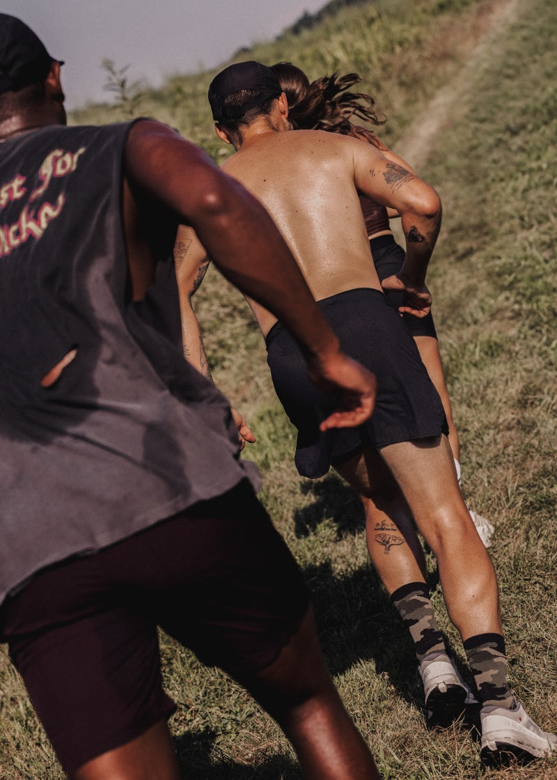 Three people running outdoors on a grassy hillside.