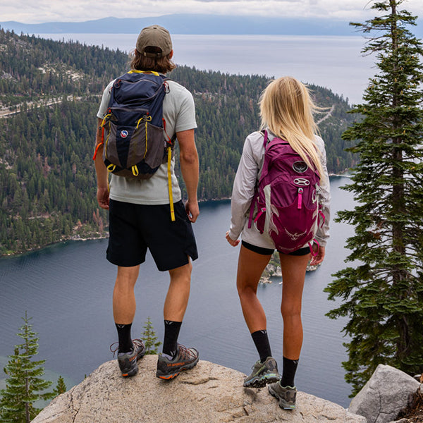 Two hikers, wearing Swiftwick socks, overlooking a lake