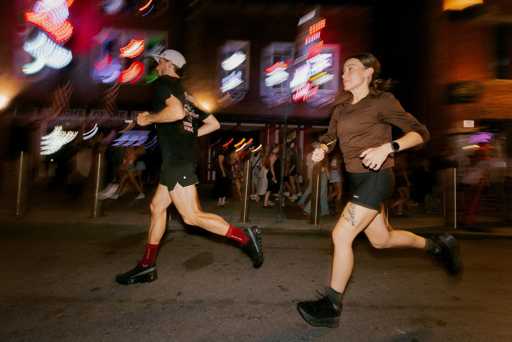 Three runners at night on a lit city street in dark athletic apparel