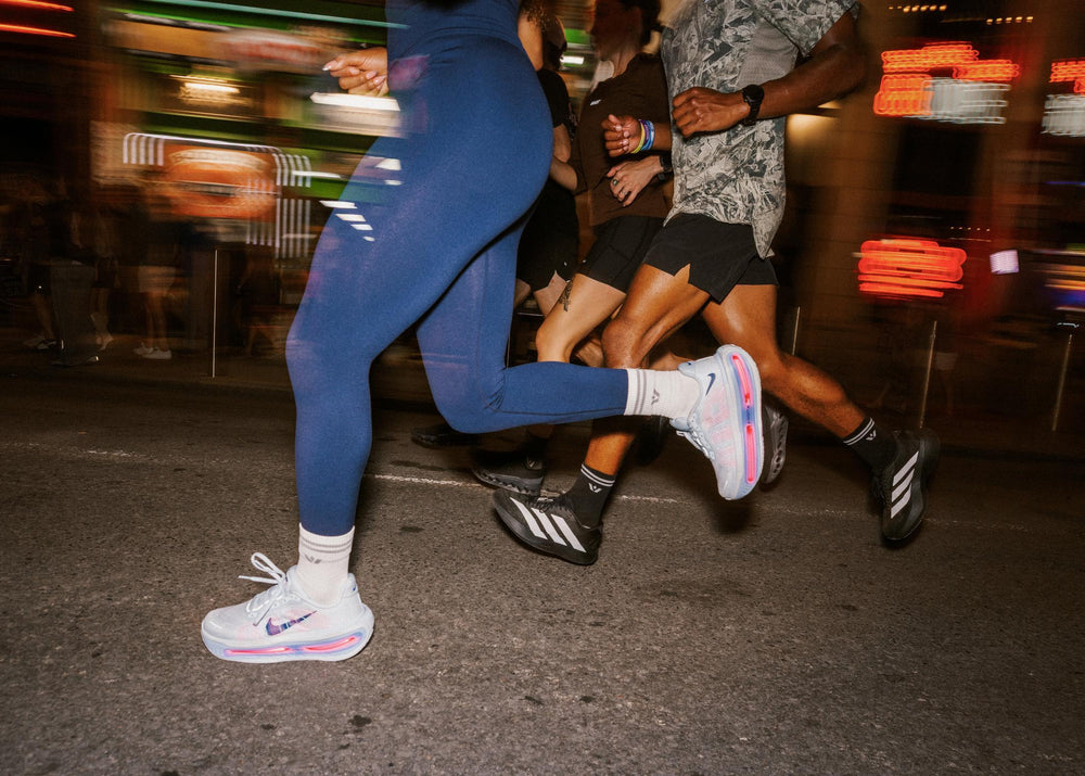 Runner at night in a blue jacket wearing Swiftwick Maxus mid crew socks