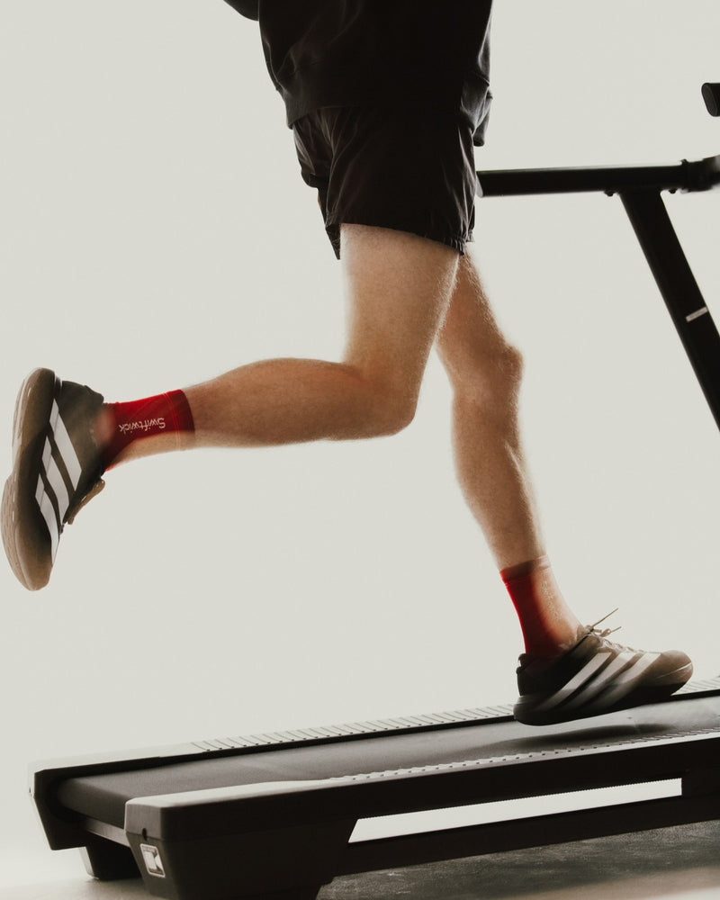 Runner on a treadmill in black shorts and red Flite XT Mid-Crew socks