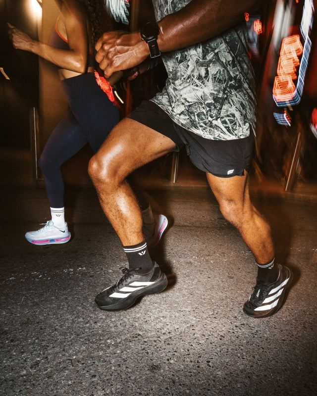 Two runners at night in dark shorts wearing Maxus black socks and sneakers