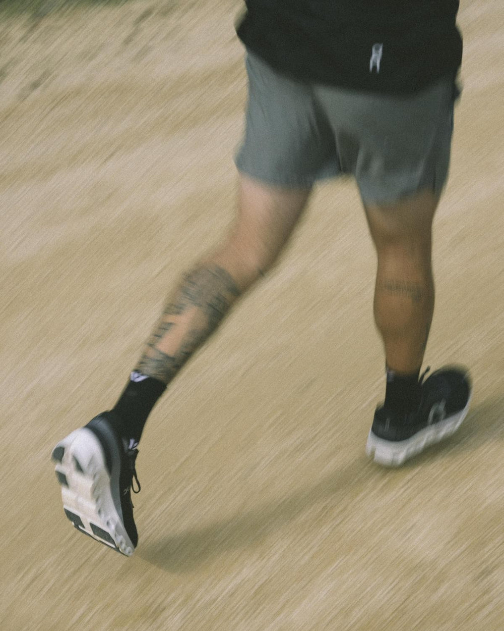 Motion-blurred action shot of a runner on a dirt path wearing black Swiftwick Maxus mid-crew socks and black running shoes.