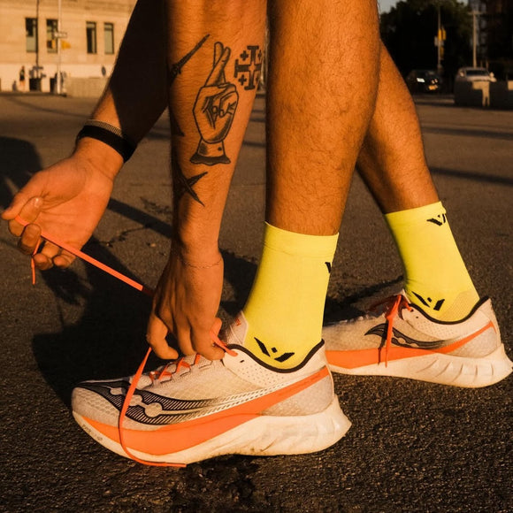 Closeup of person tying their running shoes at sunset. 